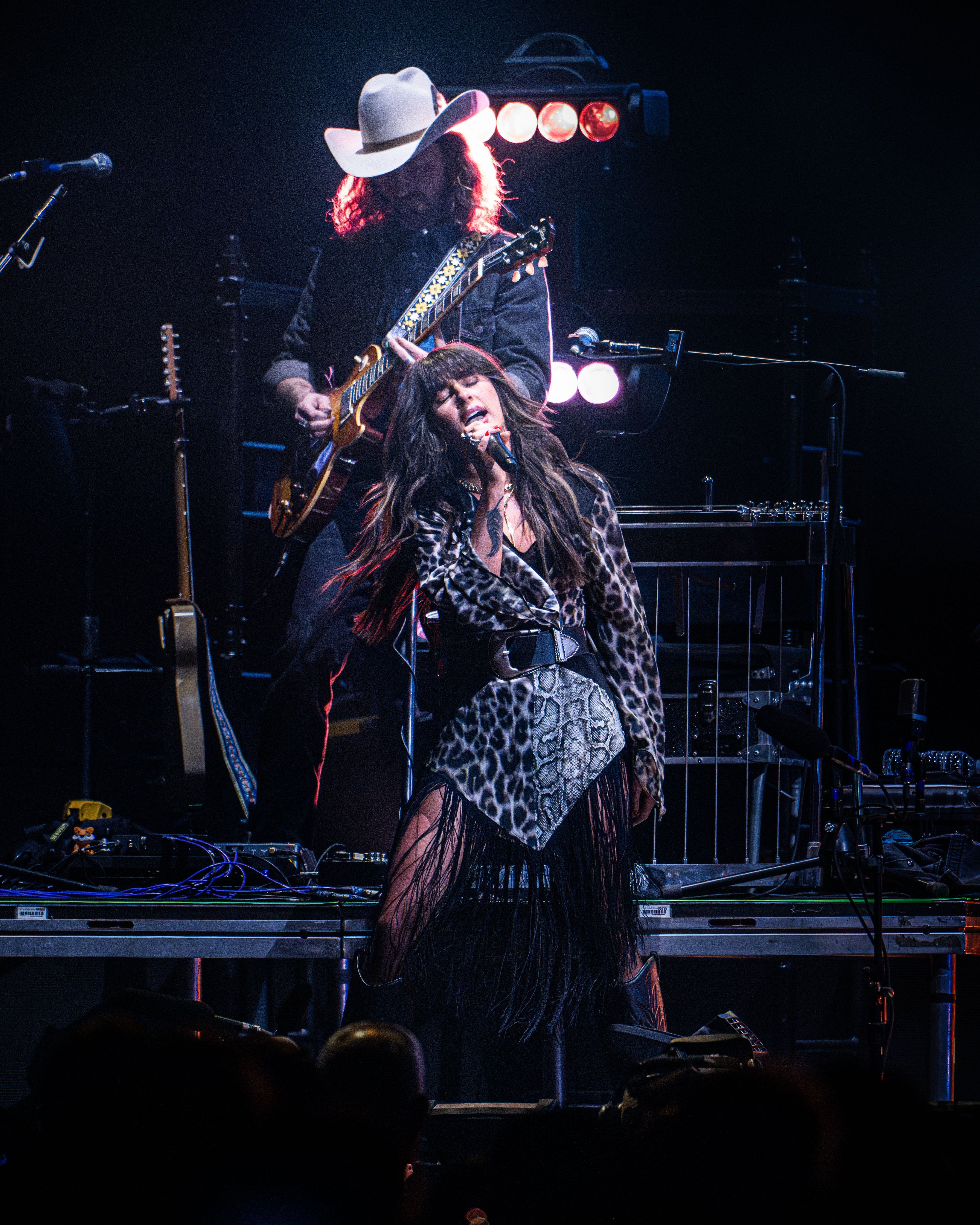 Ella Langley leaning toward a guitarist in a leopard bodysuit and fringe